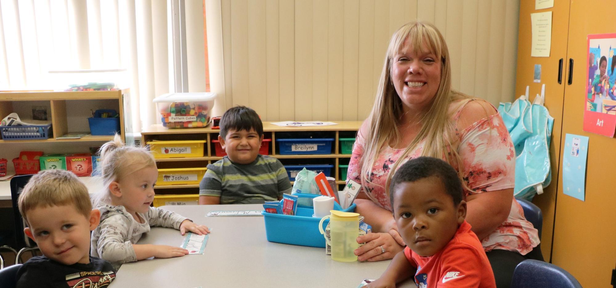 Preschool teacher and students at table